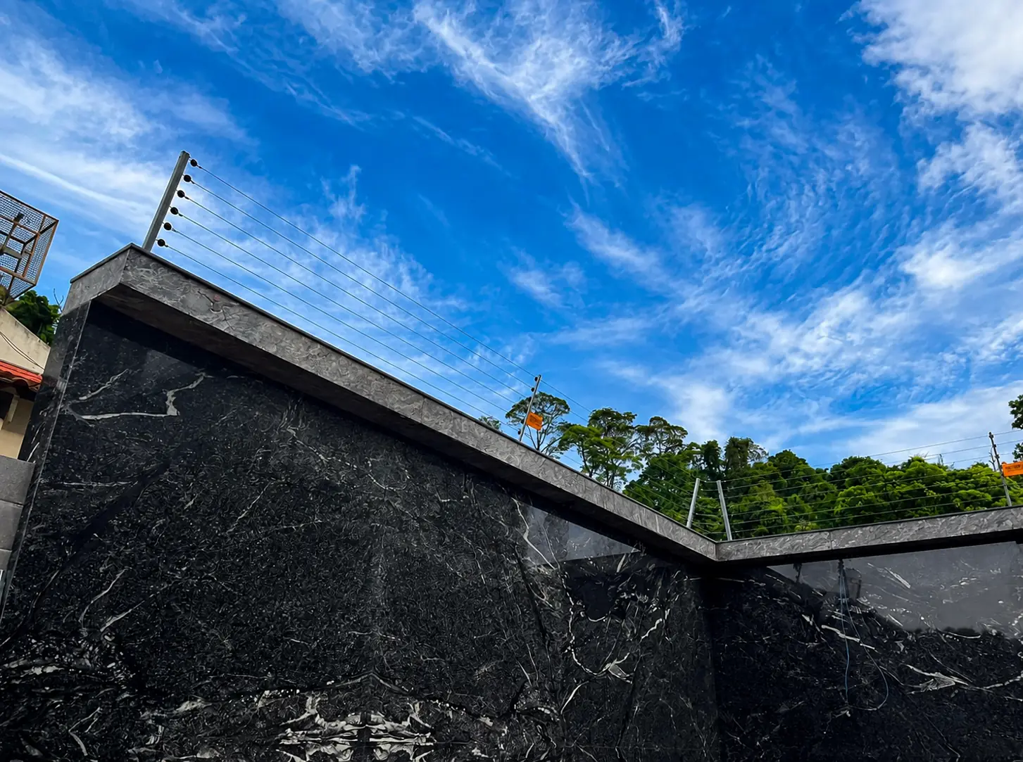 Electric fence installation above a dark stone property wall