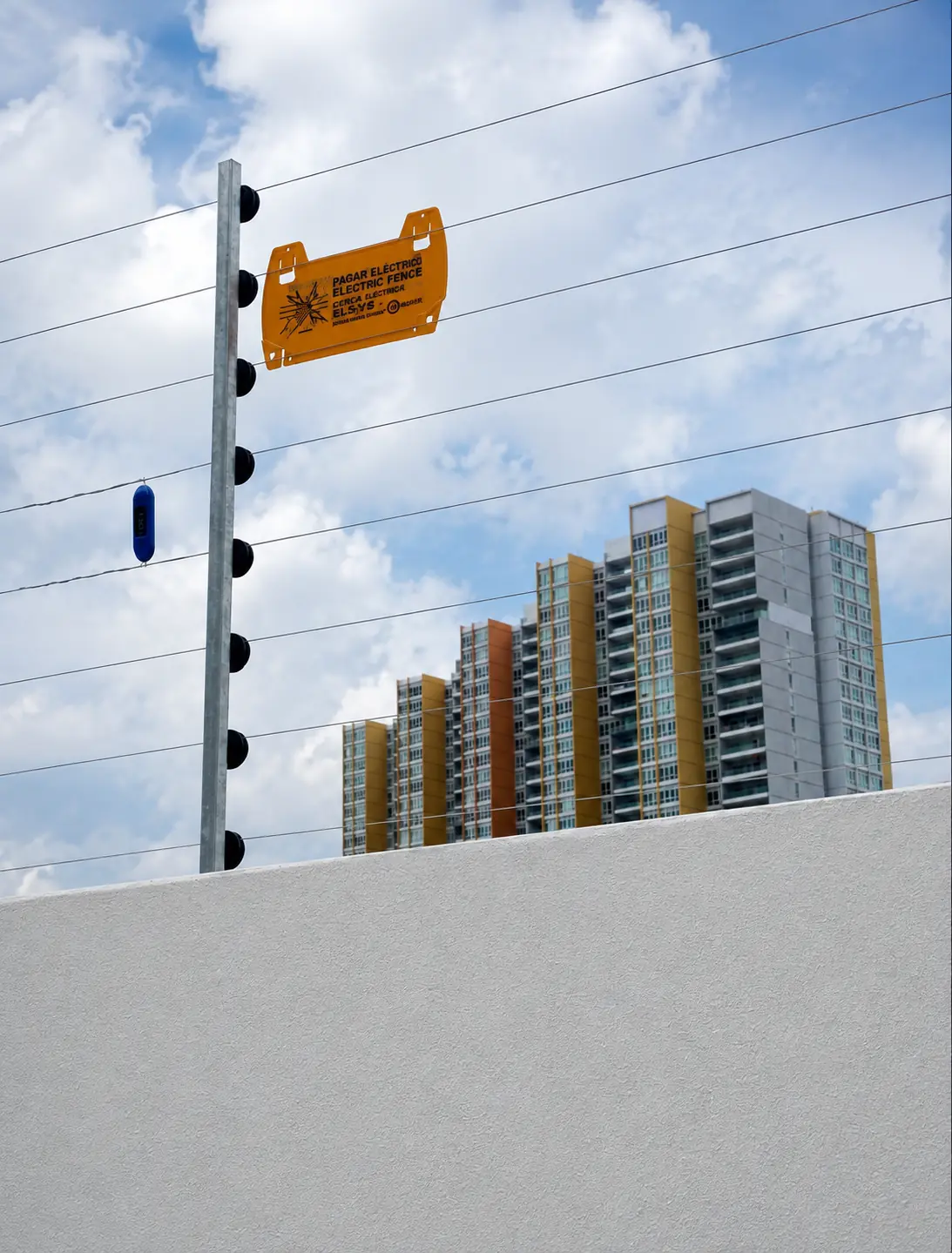 Electric fence warning sign overlooking an urban apartment boundary