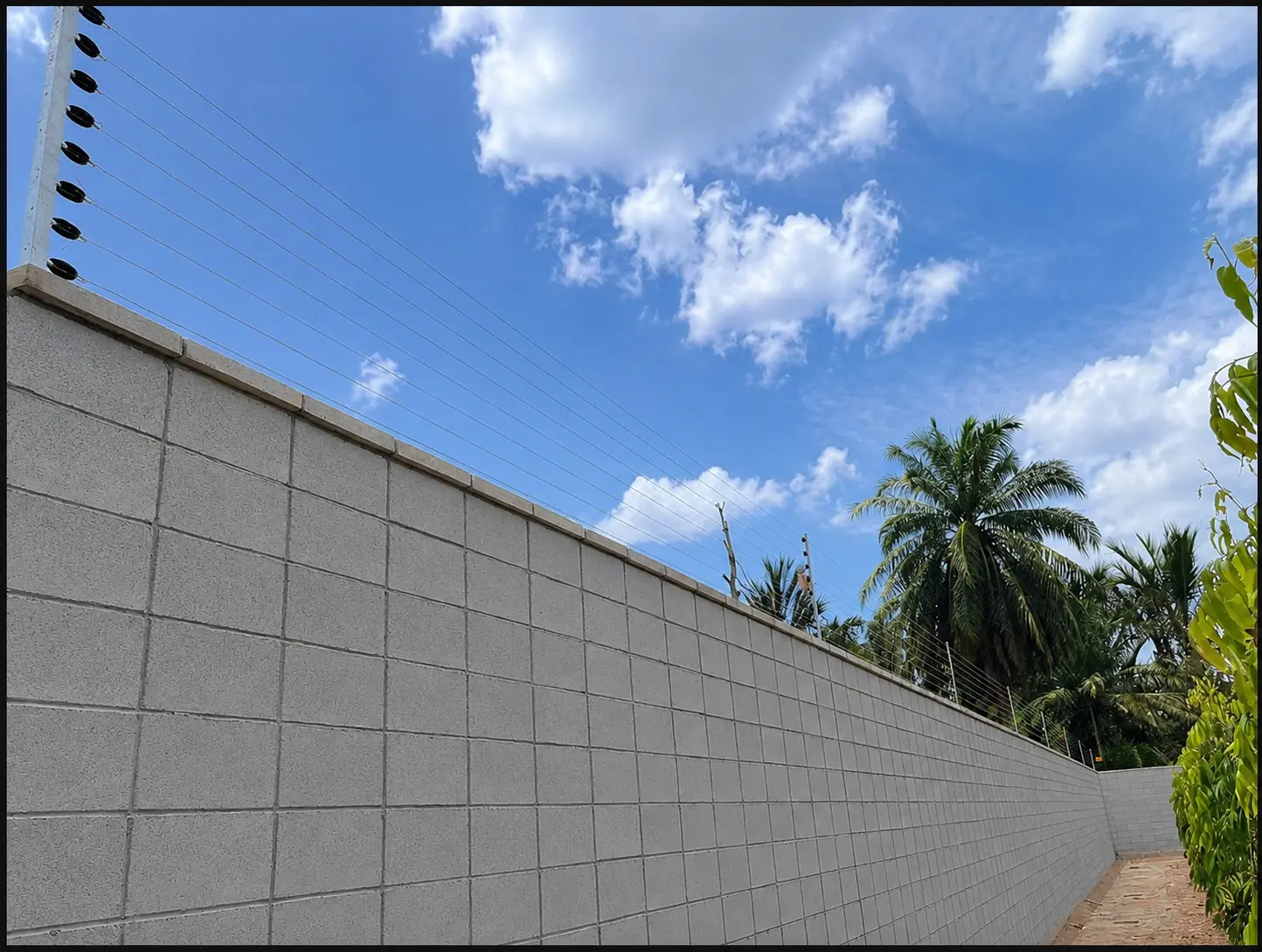 Residential perimeter security wires fitted above a concrete wall